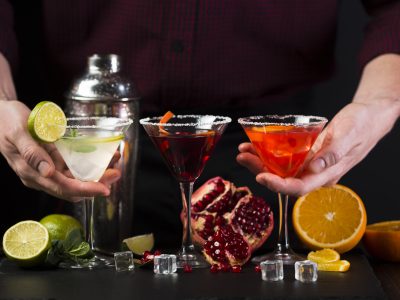 hombre sujetando coloridas copas de coctel